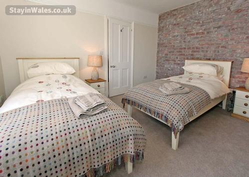 First floor twin bedroom with tasteful furnishings and exposed brickwork.