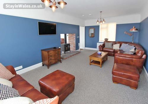 The sitting room is adjacent to the kitchen, and shares a double-fronted woodburner.