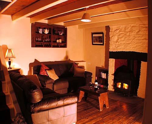 The cosy living room has a woodburner and two luxurious leather couches.