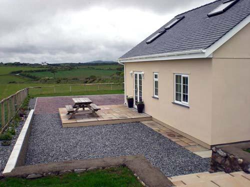 To the rear of the house is a patio area with outdoor furniture.