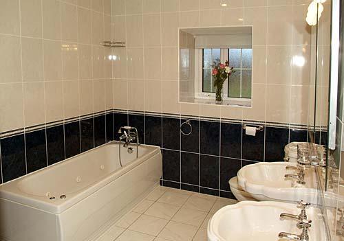 Spacious bathroom with whirlpool bath and twin wash basins at the Hendre Farmhouse