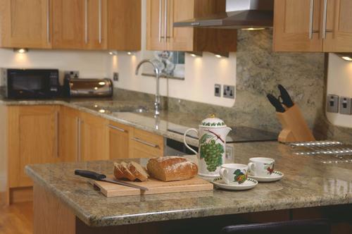 Stylish kitchen with Neff appliances and granite worktops and breakfast bar at Rhos Ddu Cottage
