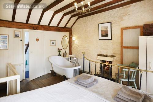 Gorgeoush spacious bedroom with comfortable kingsize bed and rolltop slipper bath in front of the fi