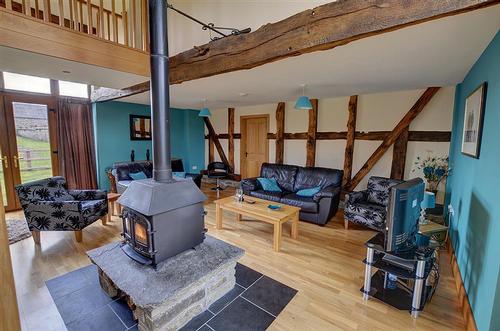 Cosy living area with double sided wood burner, large patio windows on both sides opening to a spaci