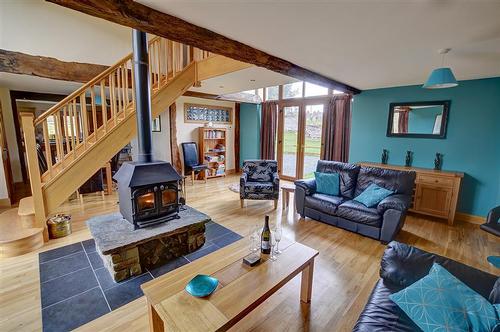 The spacious living room with central woodburner and patio doors to garden both sides.